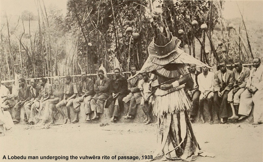Sepia archival photograph captioned as a Lobedu man undergoing the vuhwera rite of passage in 1938, with seated observers