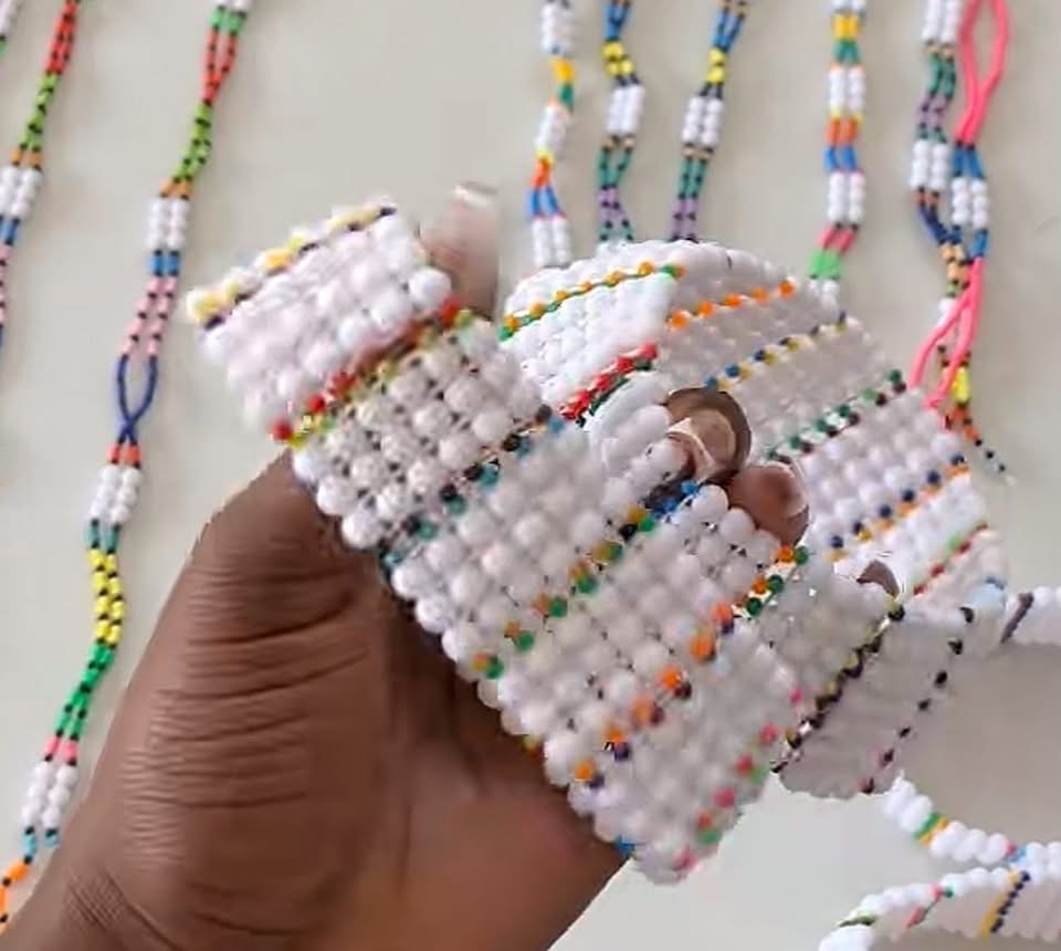 Close view of white beaded bracelets with small multicoloured beads