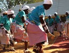 Women dancing in turquoise tops and pale pink skirts