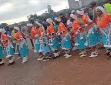 Line of dancers in turquoise and orange attire