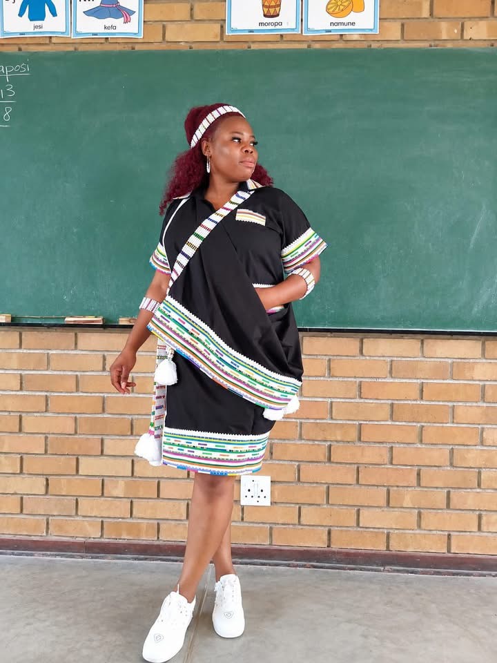 Woman wearing black attire with multicoloured bands and beaded accessories in a classroom