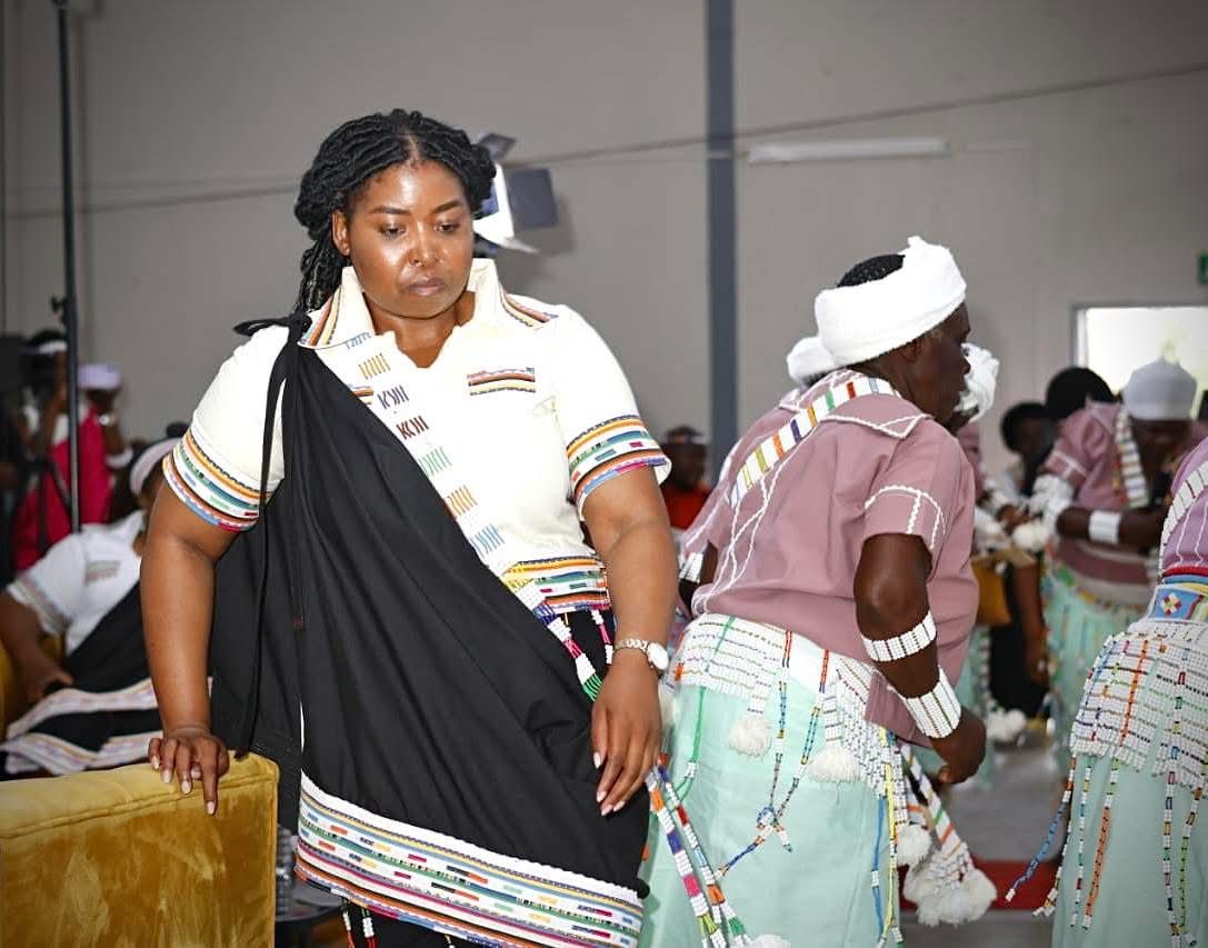 Woman wearing a black draped garment with a white top and multicoloured trim at a gathering