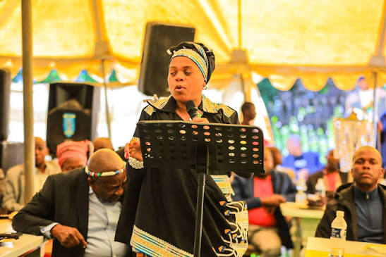Dr Phophi Ramathuba speaking into a microphone in Morina attire at the Balobedu royal capital