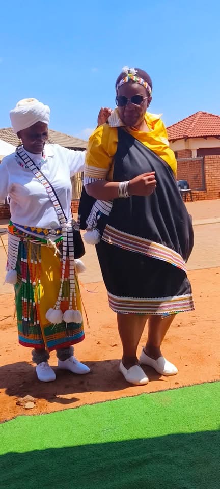 Two women outdoors in black, white and yellow attire with beadwork