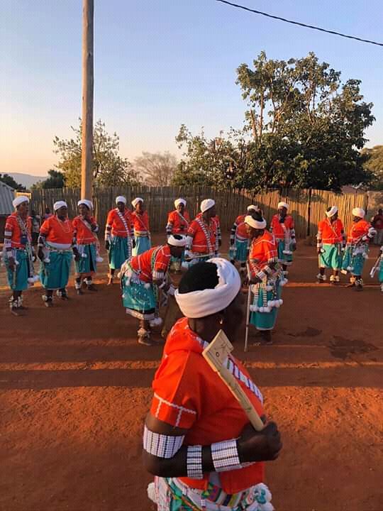 Women in orange tops and turquoise skirts gathered outdoors