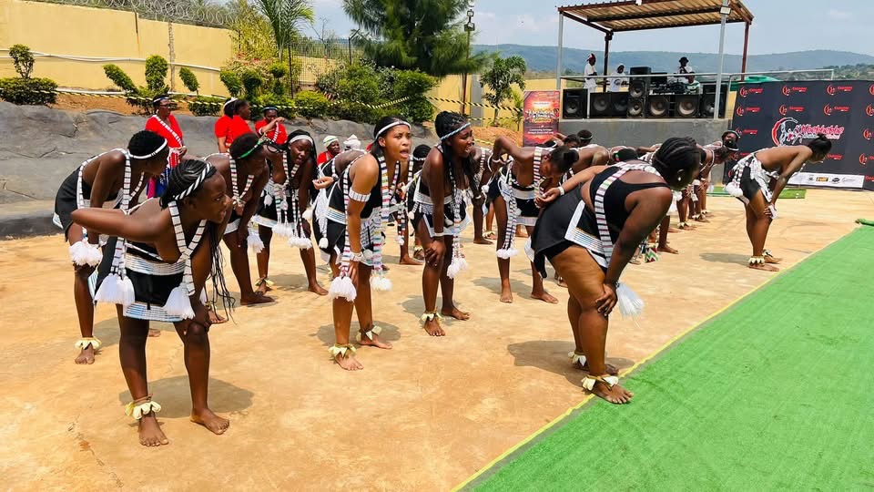 Dancers in black attire and white beadwork leaning forward in formation