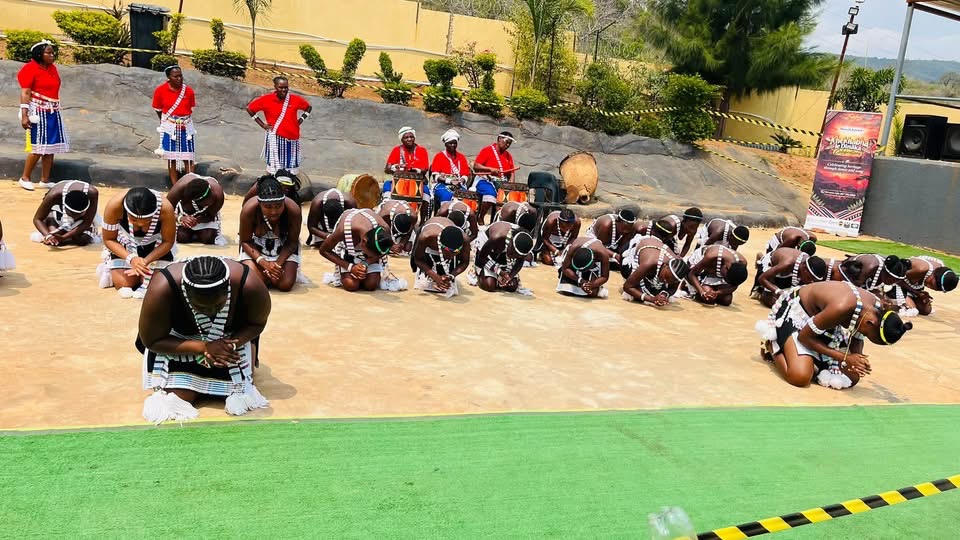 A group of dancers kneeling and bowing before drummers