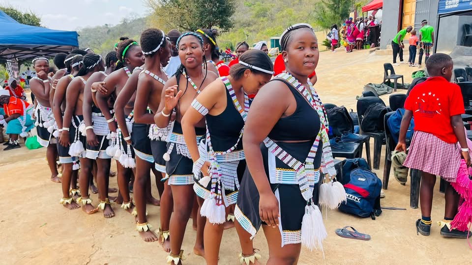 A line of young performers in black attire and white beadwork